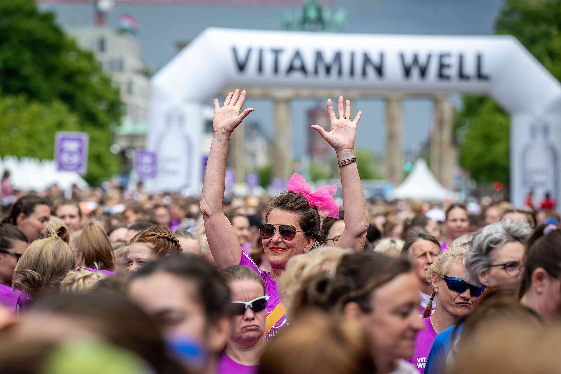 VITAMIN WELL Frauenlauf Berlin: Frau in der Masse mit Armen nach oben © SCC EVENTS / Tilo Wiedensohler